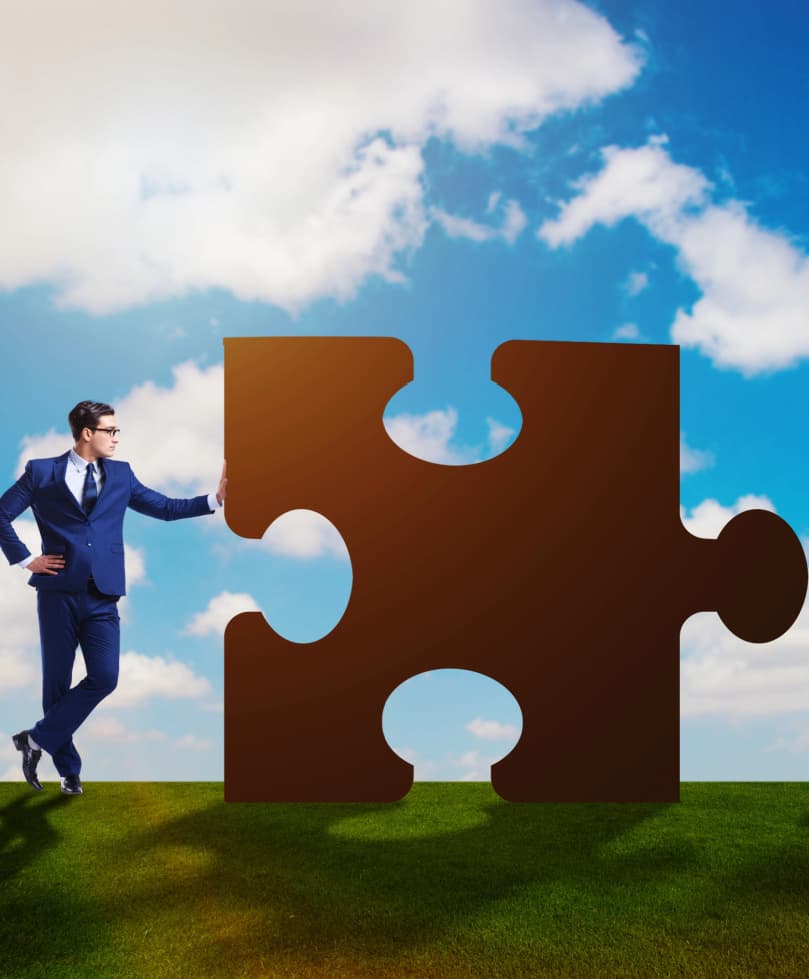 Business professional in suit standing beside a large puzzle piece, symbolizing collaboration in Canadian insolvency and debt solutions for lawyers, accountants, financial advisors, mortgage brokers, and realtors.